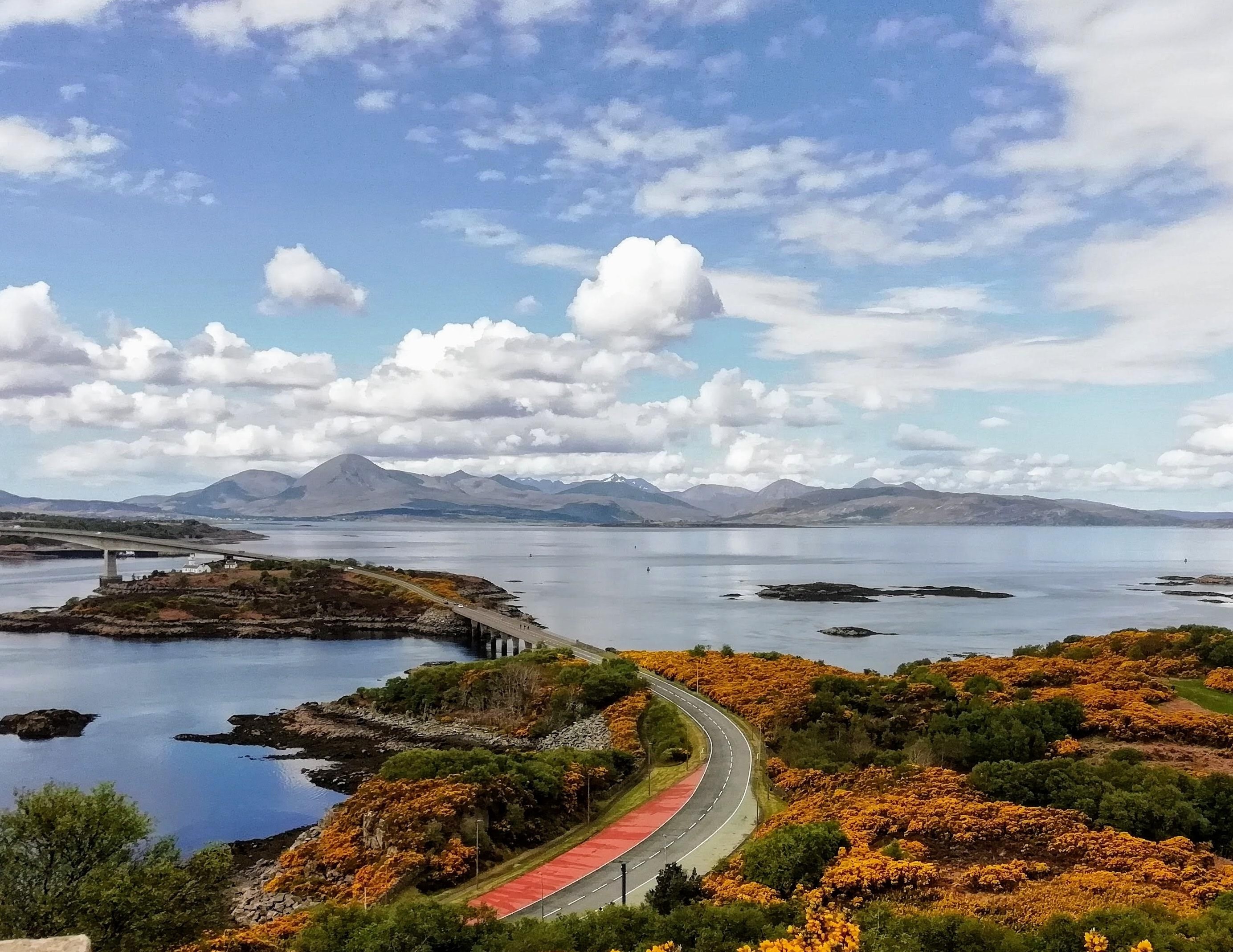 A remote viewpoint on a sunny day overlooking the Skye Bridge, beyond which is the Isle of Skye's Cuillin Hills, photographed from the Plock of Kyle, Kyle of Lochalsh, Ross Shire, Scotland image