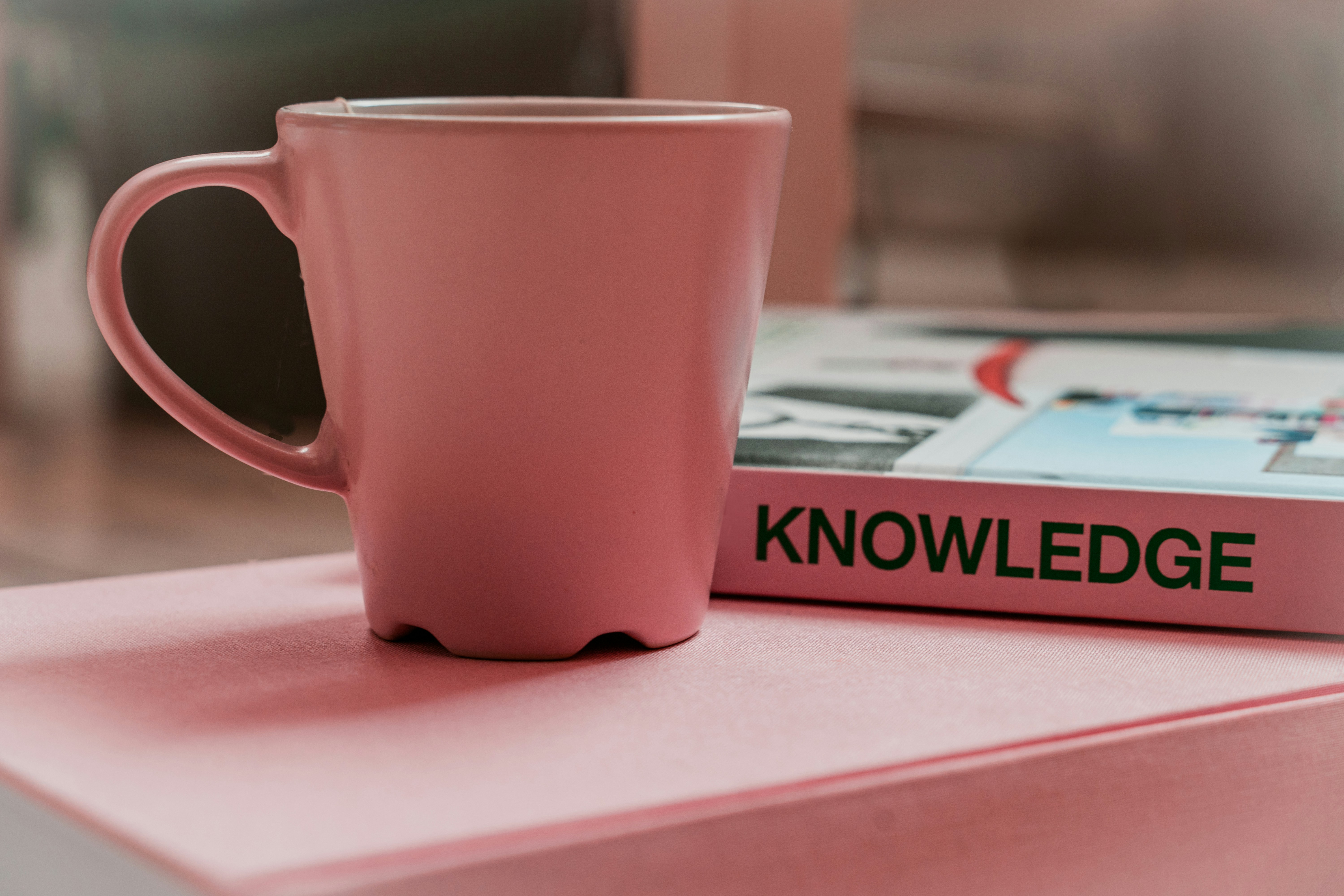 Knowledge book image with a pink mug aside image